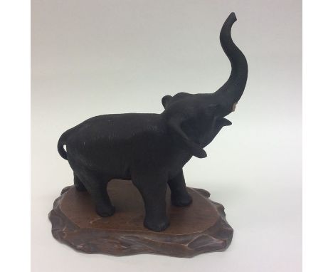 A good quality bronzed model of an elephant with textured body and outstretched trunk on wooden base. Chinese seal mark to ba