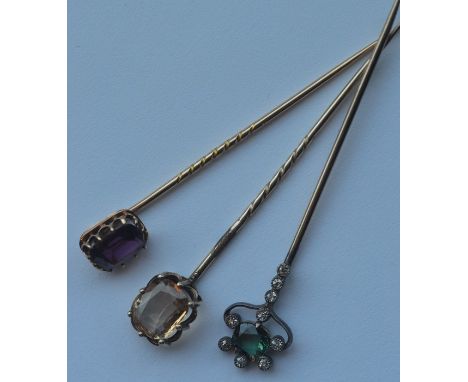 A group of three Antique gold stick pins decorated with bright stones in claw mounts. Approx. 7 grams. Est. £150 - £200.