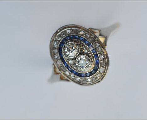 A sapphire and diamond oval cluster ring in two-colour gold mount. Approx. 4 grams. Est. £700 - £800.