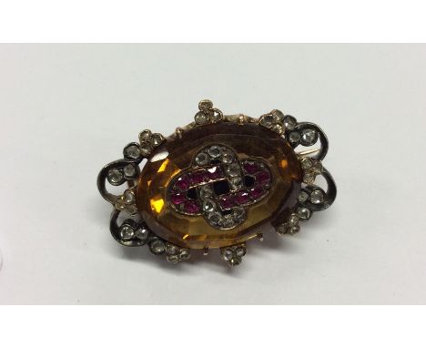 An Antique ruby, topaz and diamond oval brooch, the body decorated in claw mount. Approx. 11 grams. Est. £350 - £450.