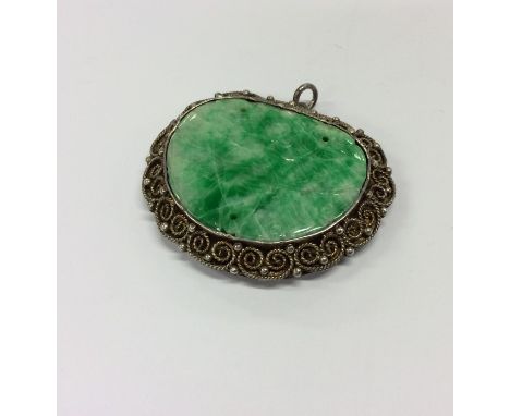 A good Chinese carved jade panel mounted as a pendant with filigree decoration. Approx. 13 grams. Est. £120 - £150.