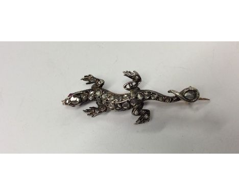 An unusual gold and silver brooch in the form of a lizard, the body decorated with diamonds and ruby eyes. Est. £350 - £400.