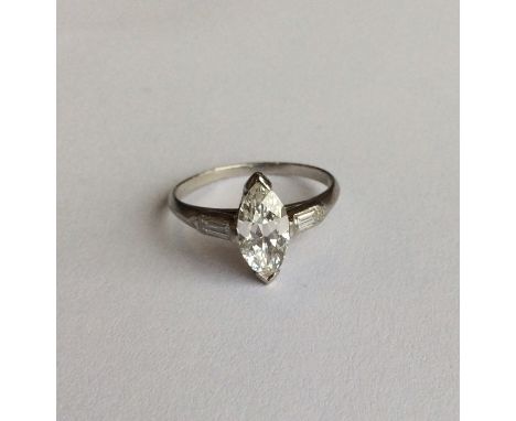 An attractive marquise single stone ring, the central stone in claw mount weighing approx. 1.05 carats, supported by baguette