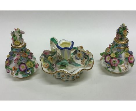 A pair of flower encrusted scent bottles with lift-off covers together with an inkwell. Est. £40 - £60.