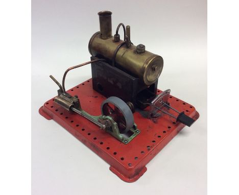 A small novelty brass steam engine on red painted base. Est. £30 - £50.