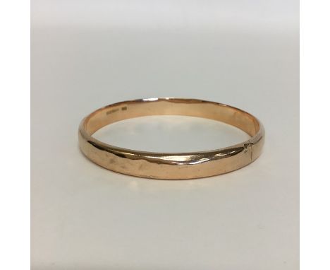 A 9 carat slave bangle of plain decoration. Approx. 14 grams. Est. £100 - £150.