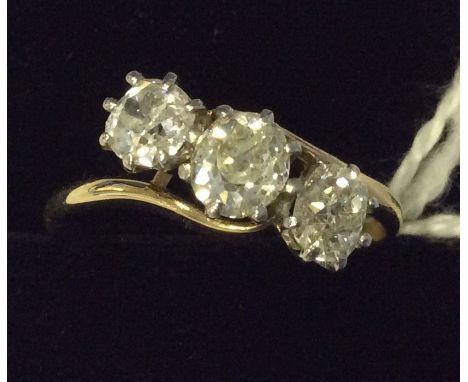 A large diamond three stone crossover ring in platinum claw mount. Approx. 1.75 carats in total. Est. £1500 - £2000.