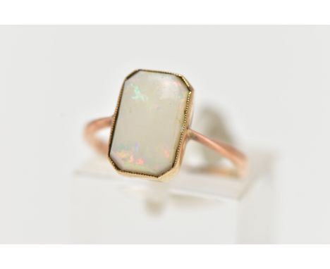A YELLOW METAL OPAL RING, rectangular cut opal cabochon with cut off corners, milgrain collet mount, pinched shoulders leadin