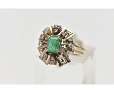 A 1970s EMERALD AND DIAMOND CLUSTER RING, of geometric design, set with a principal rectangular cut emerald, surrounded by si