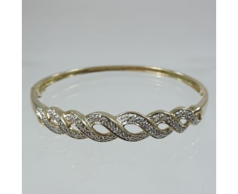 An unmarked diamond set bangle, of hinged crossover design, approximately 0.25 carat gross, 6.5cm diameter