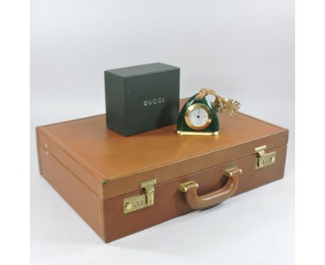 A Gucci gold plated and malachite stirrup shaped mantel clock, 9cm tall, boxed, together with a Gucci briefcase