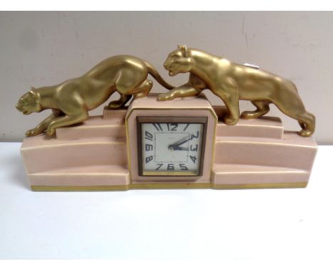 A French eight day Art Deco mantel clock surmounted by two gilt panthers 