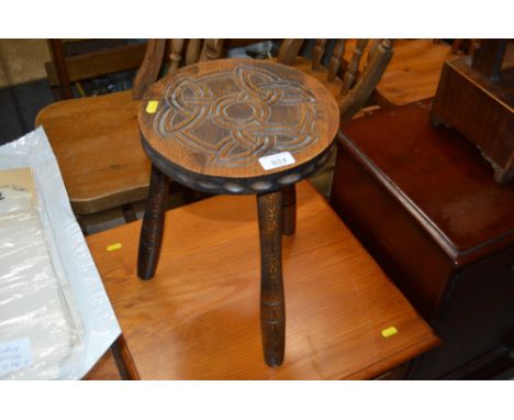 A wooden three legged stool with Celtic style carved decoration
