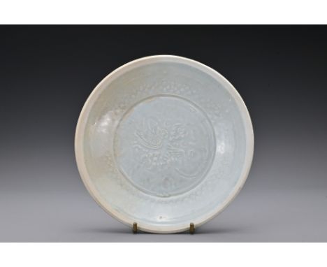 A Chinese Southern Song Dynasty (1127-1279) moulded shallow dish, covered in a light pale blue glaze leaving the rim unglazed