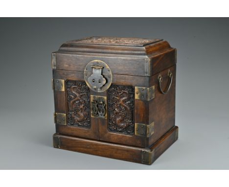 A Chinese hardwood seal chest. Of rectangular form carved in relief with dragons and clouds. Top-opening with two doors openi