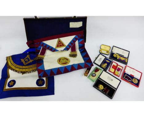 Masonic regalia to include three aprons, a sash and a collection of silver gilt medals with boxes, etc all contained within a