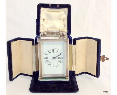A silver case carriage clock with enamel face and original velvet case