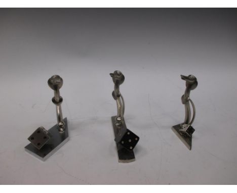 A set of three Haganauer stylised bronze dogs, mounted on a base with dice  