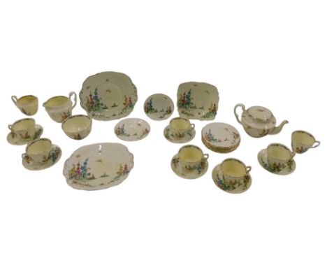 A Royal Staffordshire Art Deco Hollyhocks part tea service, decorated with coloured flowers, on a yellow ground.