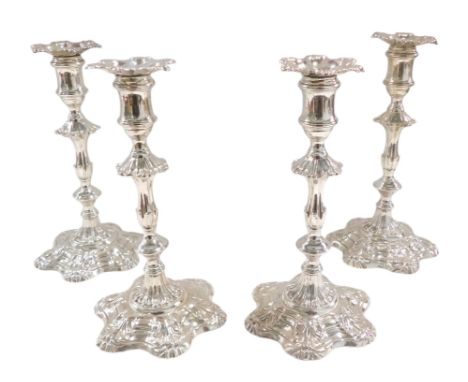 A set of four George III silver cast candlesticks by William Cafe, each with a shell cast sconce, a part scroll and turned co