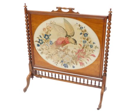 A Victorian walnut fire screen, inset with an oval woolwork banner embroidered with flowers and a parrot, on cabriole legs wi