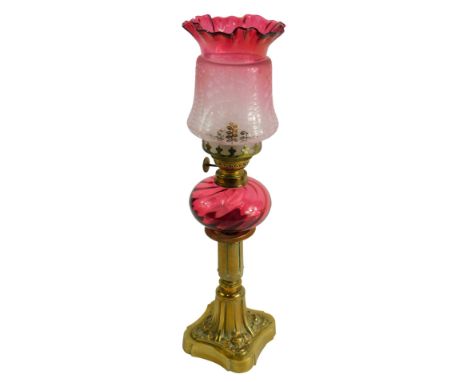 A brass and cranberry tinted oil lamp, with etched glass shade, 43cm high.