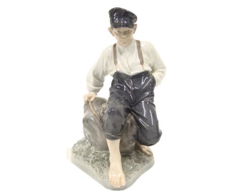 A Royal Copenhagen porcelain figure of a seated young fisherman posed on a rock, on a shaped base, printed marks and handwrit