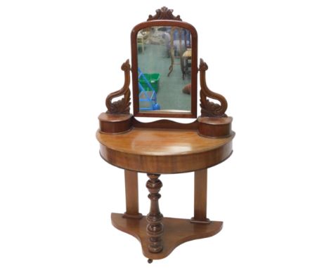 A Victorian mahogany duchess dressing table, the rectangular mirrored plate with an arched top, on leaf carved shaped support