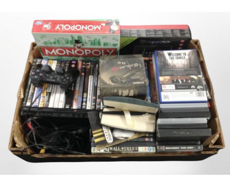 A box containing PlayStation 2 console, PS1 and PS2 games, DVDs, tablet in box, Monopoly game, cross pen in box.