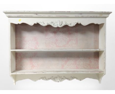 A French carved and cream painted wall shelf, width 98 cm 