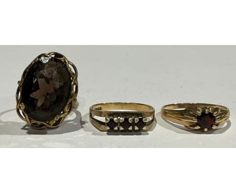 Three 9ct gold rings to include; two Almandine/Pyrope Garnet rings and a Smoky Quartz ring, the solitaire garnet ring the rin