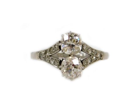 An Art Deco diamond ring, set with two old round cut stones of 8.5mm diameter each, split shoulders set with seven tiny stone