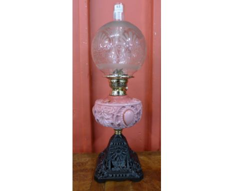 A Victorian cast iron oil lamp, with pink glass reservoir