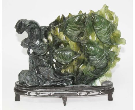 A Chinese jadeite jade carving depicting four carp and two cat fish with seaweed background, on wood base, 20th century, heig