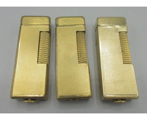 Dunhill Patented gold plated butane cigarette lighter, engine turned decoration and two similar lighters, H6.4cm 