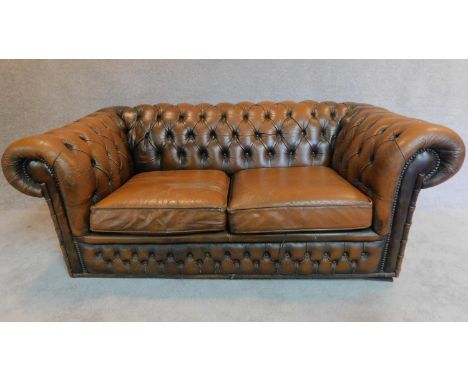 A two seater brown leather chesterfield sofa. H.68 W.163 D.84cm 