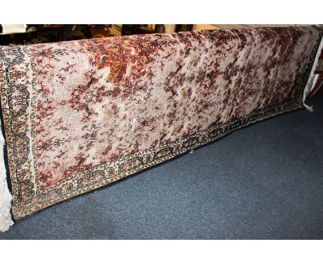 A Kashmir silk carpet with all over pattern of birds, beasts and flowers on red ground (a/f), 325cm by 234cm