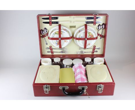 A 1950's Brexton picnic hamper with porcelain plates, cups and saucers for four, with various tins and jars, etc, in red faux