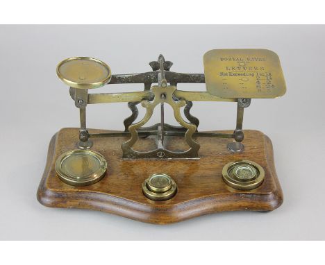 A set of brass postal scales with weights, on wooden base