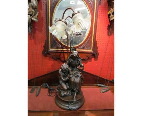 A bronzed resin "Confidence" figural lamp with twin branches, 73cm height 