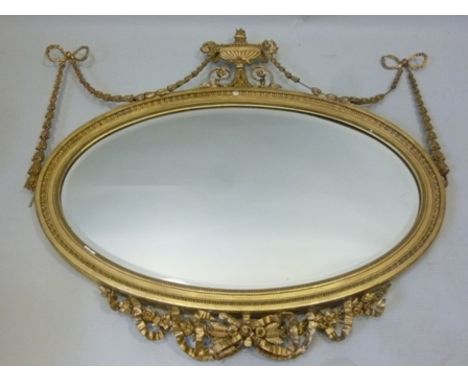 A 19TH CENTURY ADAM'S STYLE GILT FRAMED OVAL BEVEL PLATE WALL MIRROR, the frame decorated with central urn, profuse bow toppe