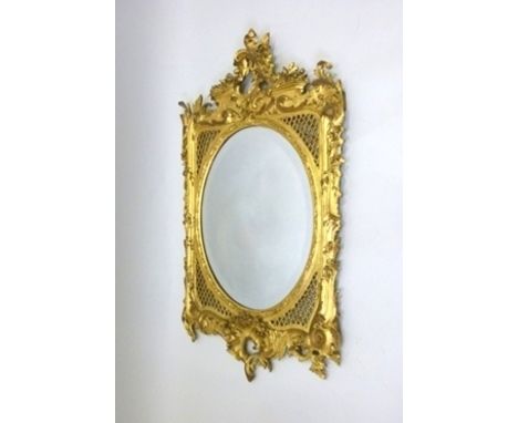A CHIPPENDALE STYLE MIRROR, having ornate giltwood and gesso surround with foliate and fretted carving, around an oval bevell
