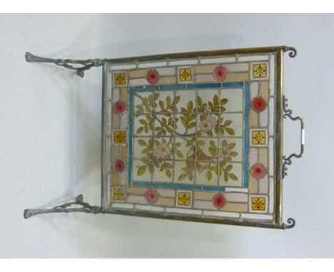 A BRASS FRAMED ARTS & CRAFTS PERIOD FIRE SCREEN formed from a stained glass panel, the central section painted with a bird am