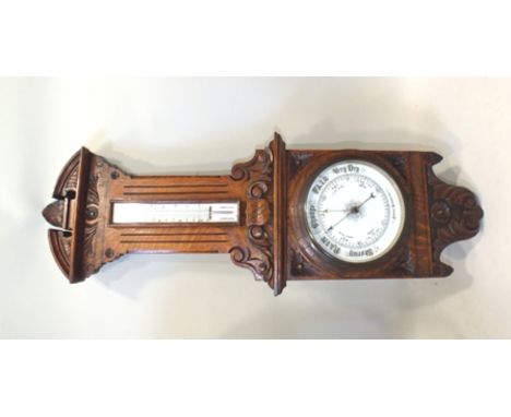 AN EDWARDIAN CARVED OAK CASED BAROMETER/THERMOMETER, dial 19cm, 92cm high 