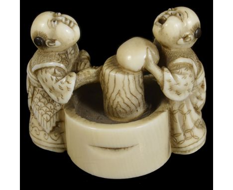 ˜A JAPANESE IVORY NETSUKE OF BOYS MAKING MOCHI, MEIJI PERIOD (1868-1912) standing either side of a large mortar, signed Tomok