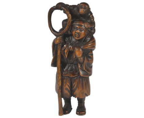 A JAPANESE WOOD NETSUKE OF A STANDING SARUMAWASHI, LATE MEIJI PERIOD, CIRCA 1910 standing with his monkey on his shoulder, si
