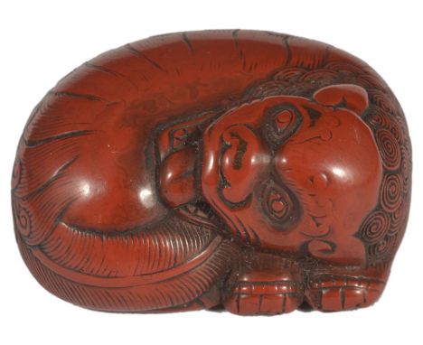 A JAPANESE RED LACQUER NETSUKE OF A SHISHI, LATE EDO PERIOD, CIRCA 1800 in Chinese style, curled up and with its tongue out, 