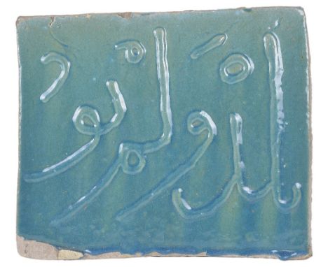 A PERSIAN TURQUOISE GLAZED TILE glazed fritware, of rectangular form, a line of applique relief Arabic lettering 28 x 33cm Pr