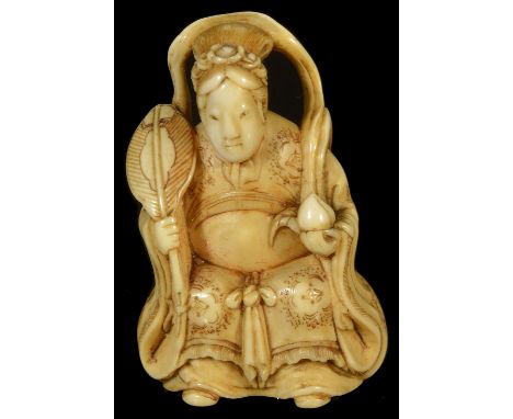 ˜A JAPANESE IVORY NETSUKE OF SEIOBO, LATE EDO PERIOD, CIRCA 1860 seated on a stool and holding a peach and fan, unsigned, but