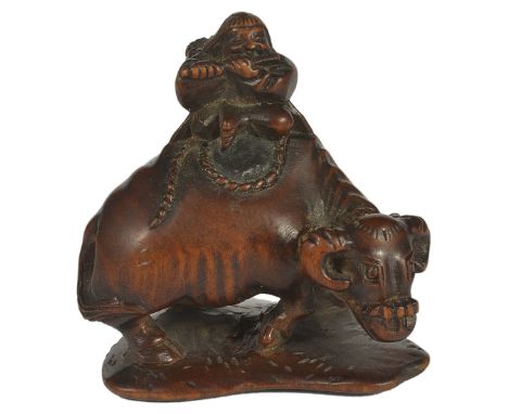 A JAPANESE WOOD NETSUKE OF A HERD-BOY ON AN OX, LATE EDO PERIOD, CIRCA 1850 with a basket on his back, and playing a flute, o